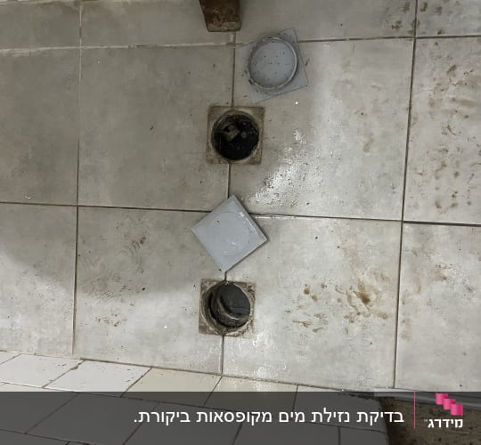 פתחי ניקוז פתוחים ברצפה עם מכסים מונחים בצד